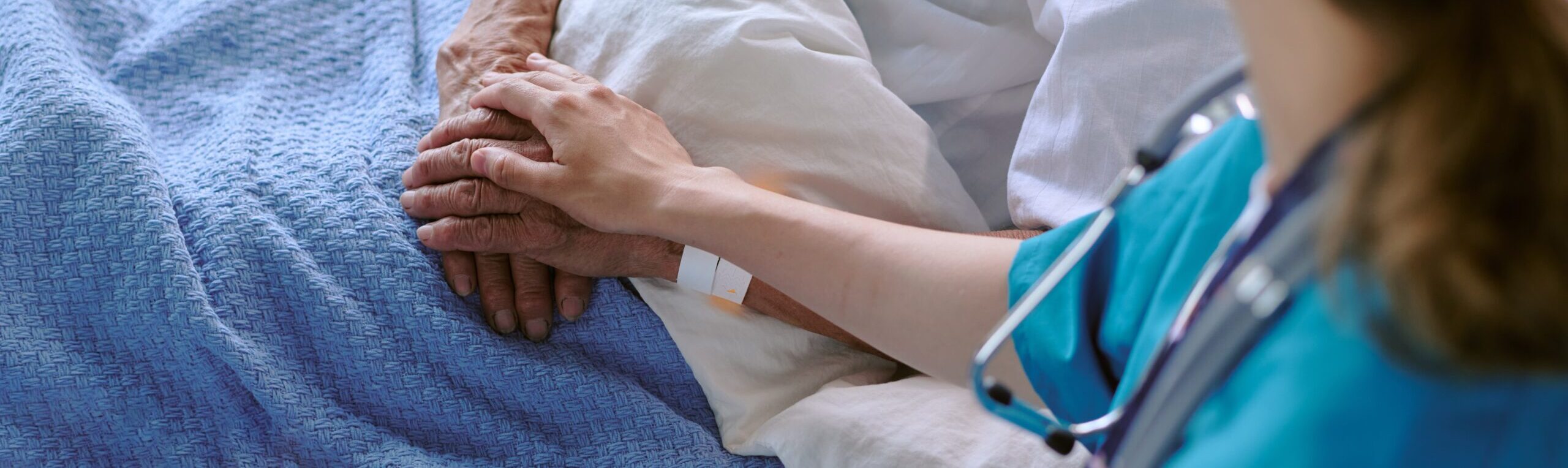 Senior,Patient,Lying,In,Hospital,Bed,Receiving,Comforting,Touch,From